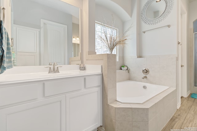 bathroom with vanity, hardwood / wood-style flooring, and tiled tub