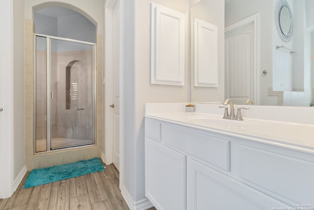 bathroom with wood-type flooring, vanity, and an enclosed shower