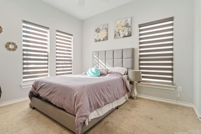 carpeted bedroom featuring multiple windows and ceiling fan