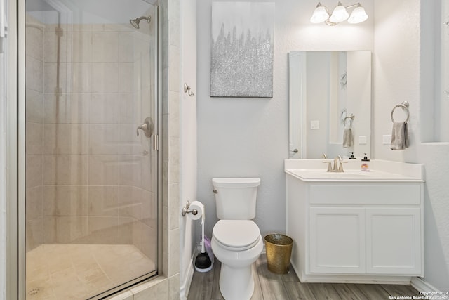 bathroom featuring hardwood / wood-style floors, a shower with shower door, vanity, and toilet