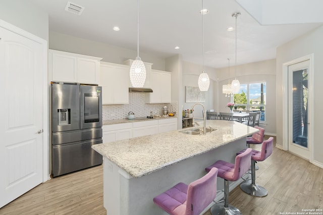 kitchen with a kitchen island with sink, white cabinetry, sink, and stainless steel fridge with ice dispenser