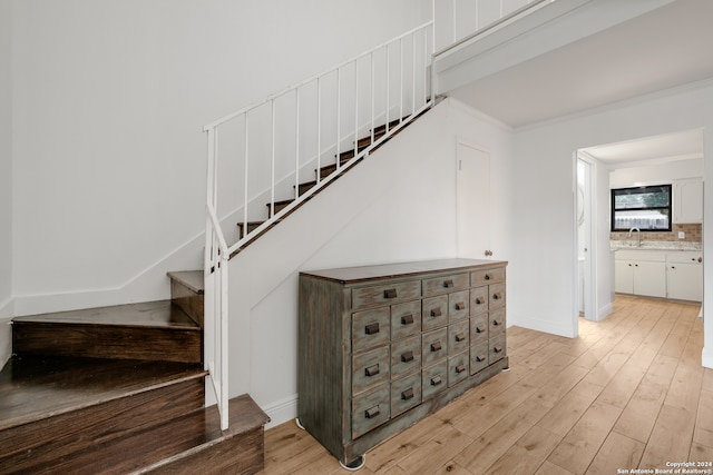 staircase with wood-type flooring and ornamental molding