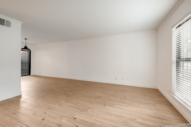 empty room with ornamental molding and light hardwood / wood-style floors