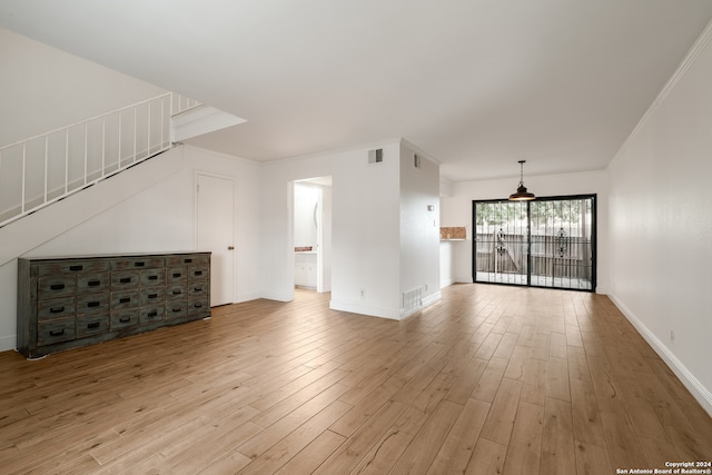 unfurnished living room with light wood-type flooring and crown molding