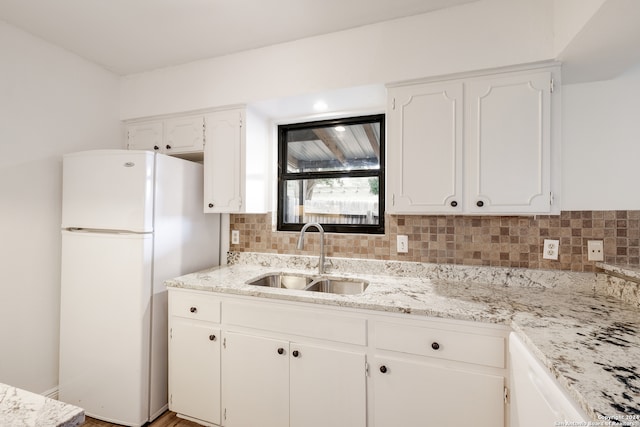 kitchen with white cabinets, decorative backsplash, sink, and white fridge