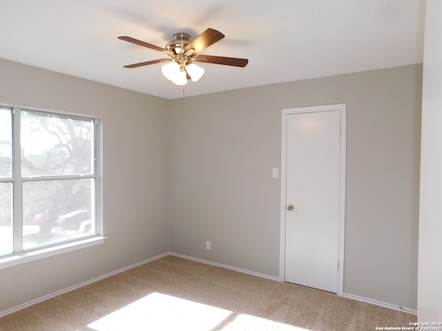 empty room with a wealth of natural light, ceiling fan, and carpet floors