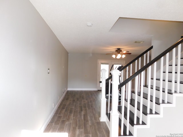 stairway featuring ceiling fan, wood-type flooring, and a textured ceiling