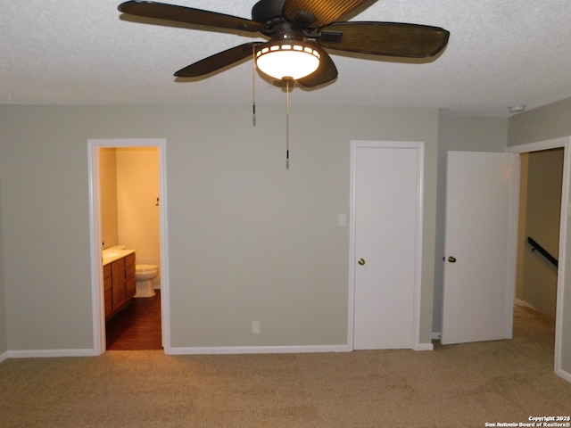 unfurnished bedroom featuring a textured ceiling, light carpet, ceiling fan, and connected bathroom