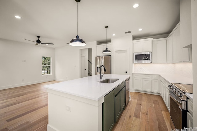 kitchen featuring white cabinetry, appliances with stainless steel finishes, light wood-type flooring, pendant lighting, and sink