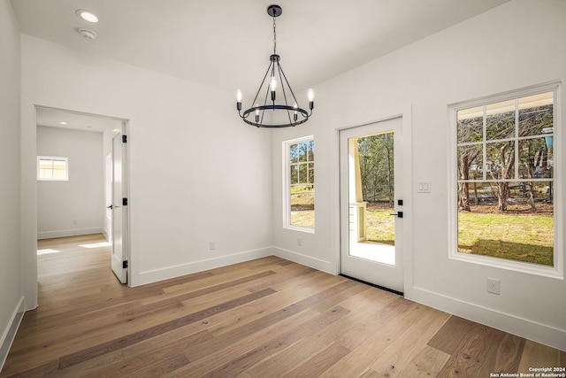 unfurnished dining area featuring hardwood / wood-style flooring and a chandelier