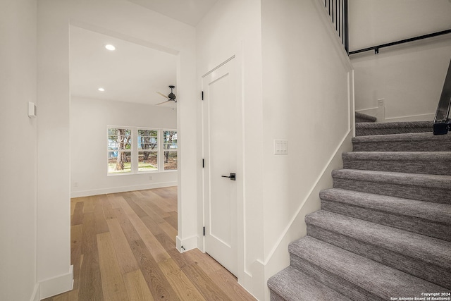 stairs with wood-type flooring and ceiling fan