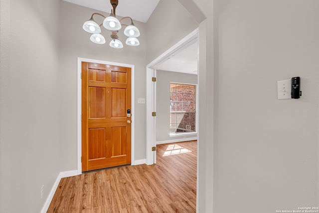 foyer entrance with light hardwood / wood-style floors and a chandelier