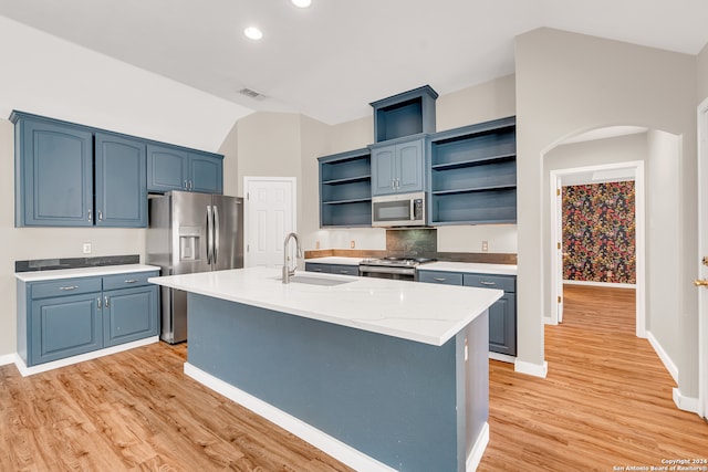 kitchen featuring sink, appliances with stainless steel finishes, light hardwood / wood-style flooring, a kitchen island with sink, and blue cabinets