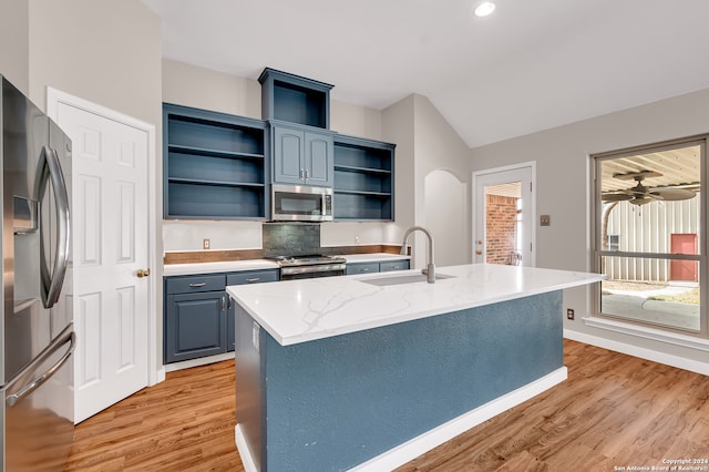 kitchen featuring appliances with stainless steel finishes, sink, an island with sink, light hardwood / wood-style floors, and blue cabinets