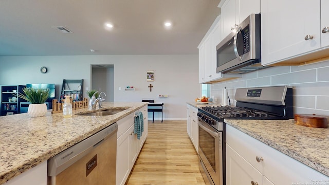 kitchen featuring stainless steel appliances, sink, light stone countertops, light hardwood / wood-style flooring, and white cabinets