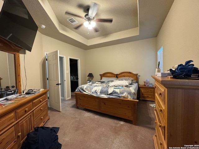 carpeted bedroom with ceiling fan, a textured ceiling, and a tray ceiling