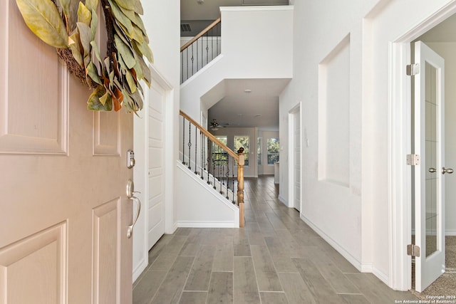 foyer entrance with ceiling fan, light hardwood / wood-style floors, and a towering ceiling