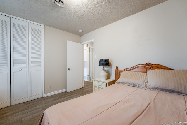 bedroom featuring light hardwood / wood-style floors, a textured ceiling, and a closet