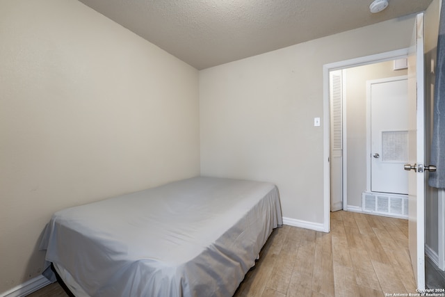 bedroom featuring a textured ceiling and light wood-type flooring