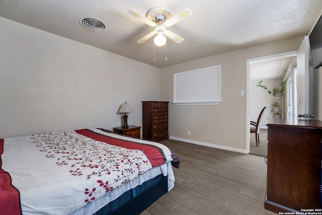 bedroom with hardwood / wood-style flooring, ceiling fan, and a textured ceiling