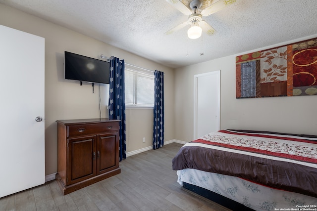 bedroom featuring light wood-type flooring, a textured ceiling, and ceiling fan