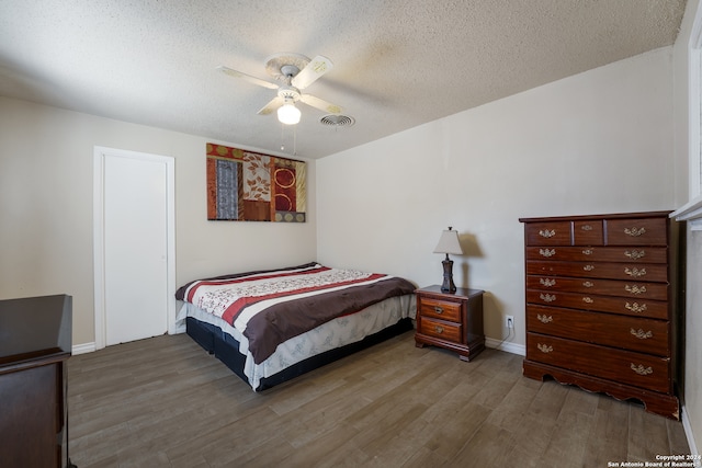 bedroom with wood-type flooring, ceiling fan, and a textured ceiling