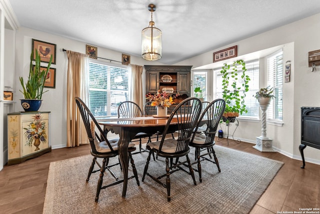 dining room with dark wood-type flooring, a wealth of natural light, a textured ceiling, and a notable chandelier