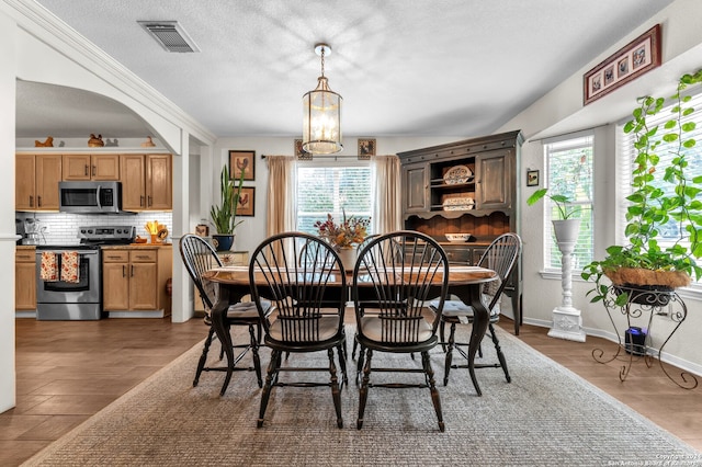 dining room with dark hardwood / wood-style flooring, a wealth of natural light, an inviting chandelier, and crown molding