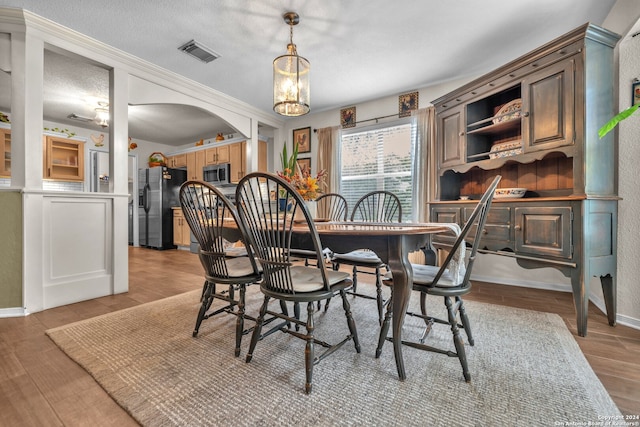 dining area featuring light hardwood / wood-style floors, a chandelier, and a textured ceiling