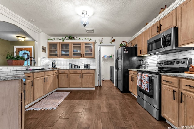 kitchen featuring tasteful backsplash, stainless steel appliances, a textured ceiling, sink, and dark wood-type flooring