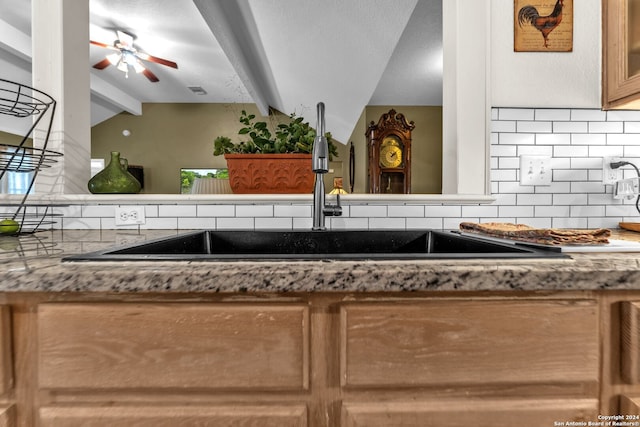 kitchen with ceiling fan, sink, vaulted ceiling with beams, and decorative backsplash