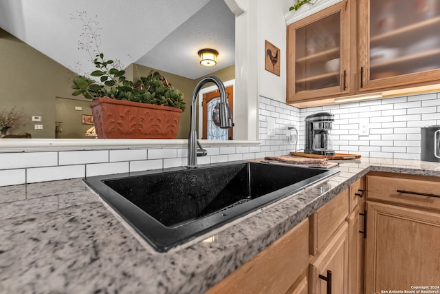 kitchen with light stone countertops, a textured ceiling, sink, and decorative backsplash