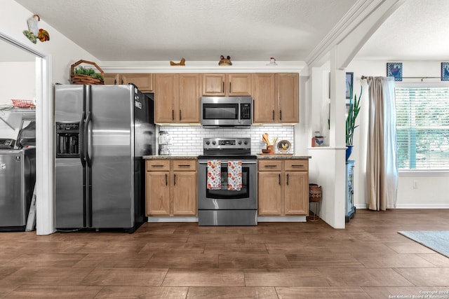 kitchen featuring appliances with stainless steel finishes, washer / clothes dryer, a textured ceiling, and backsplash