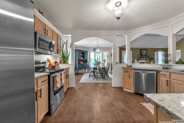 kitchen with stainless steel appliances, dark wood-type flooring, a textured ceiling, tasteful backsplash, and light stone countertops