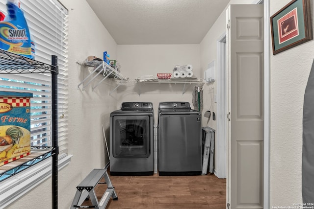 laundry room with washer and clothes dryer, a textured ceiling, and hardwood / wood-style flooring