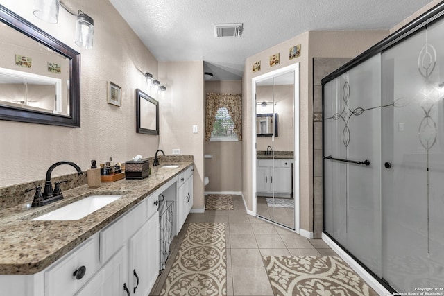 bathroom featuring walk in shower, vanity, a textured ceiling, tile patterned flooring, and toilet