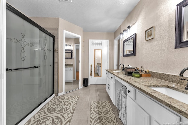 bathroom with walk in shower, vanity, a textured ceiling, and tile patterned flooring