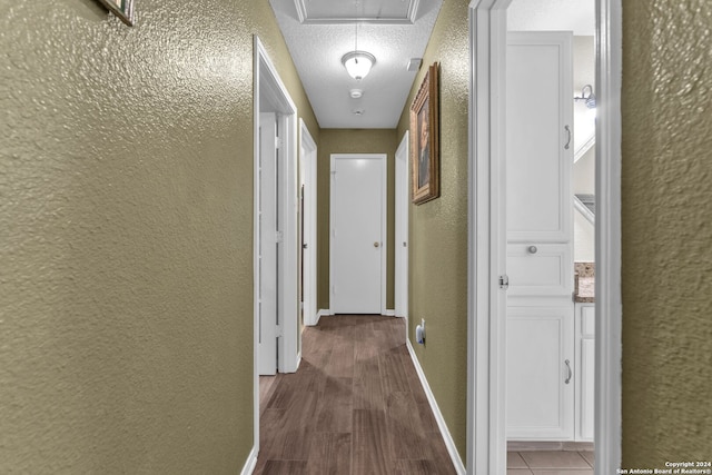 hallway with wood-type flooring and a textured ceiling