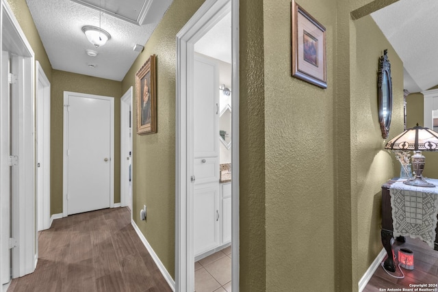 corridor featuring wood-type flooring and a textured ceiling