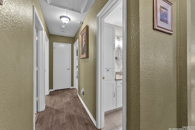 corridor with a textured ceiling and light hardwood / wood-style flooring