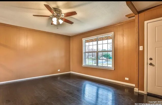 unfurnished room featuring ceiling fan, a textured ceiling, wooden walls, and dark hardwood / wood-style flooring