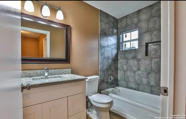 full bathroom with toilet, vanity, and tiled shower / bath