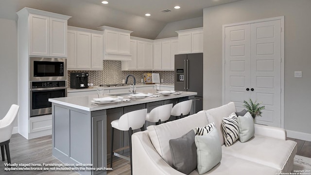kitchen with stainless steel appliances, backsplash, white cabinets, light countertops, and recessed lighting