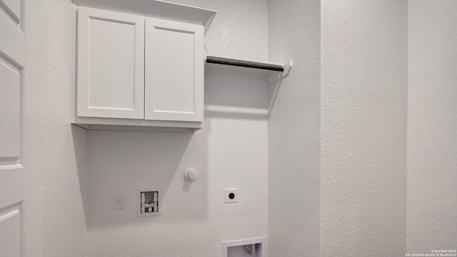clothes washing area featuring electric dryer hookup, washer hookup, cabinet space, a textured wall, and hookup for a gas dryer