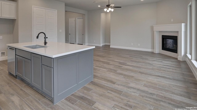 kitchen with gray cabinets, a sink, open floor plan, a ceiling fan, and dishwasher