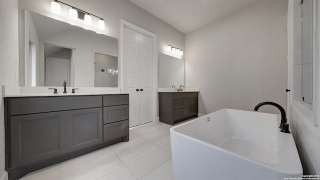 bathroom with tiled shower, two vanities, a sink, and tile patterned floors