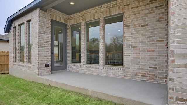 entrance to property featuring fence and brick siding