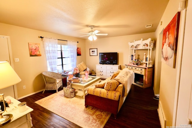 living room with ceiling fan, a textured ceiling, and dark hardwood / wood-style floors