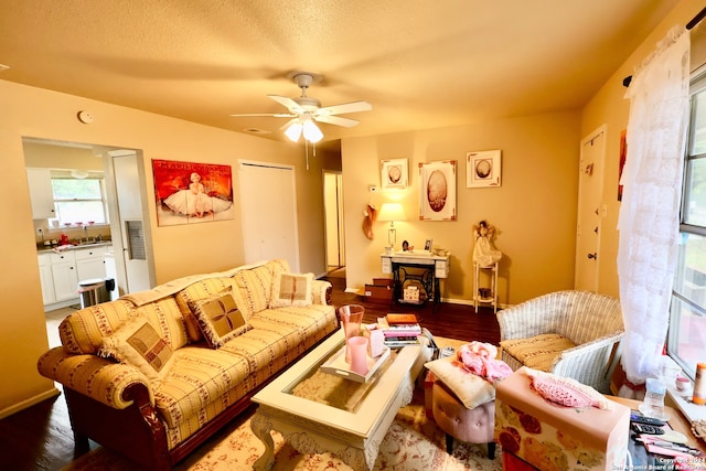 living room with a textured ceiling, dark wood-type flooring, and ceiling fan