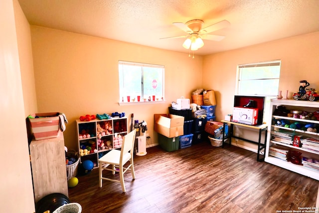 playroom featuring a wealth of natural light, ceiling fan, a textured ceiling, and dark hardwood / wood-style flooring